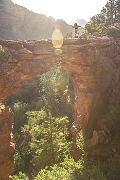 A female hiker runs across Devil's Bridge in Sedona, Arizona at sunrise.