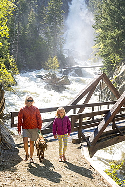 Front view shot of mother, daughter and dog hiking near waterfall, Steamboat Springs, Colorado, USA