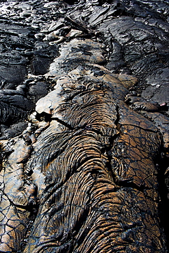 Cooled lava abstract with a bright orange vibrant color to it along the famed Puna Coast Trail to Halape Beach. The trail is 11.3 miles of rugged hiking for backpackers with no shade or water in the extreme terrain of Hawaii Volcanoes National Park, Hawaii Islands, USA