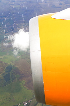 Jet engine of airplane flying over wind farm, Scotland, UK