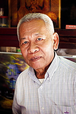 Head and shoulders portrait of mature man with gray hair looking at camera, Kerala, India