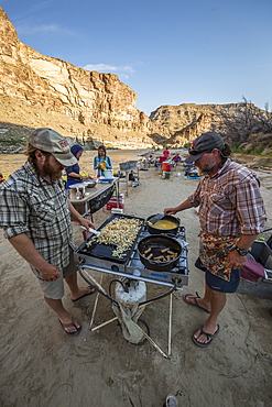 Two men cooking meal in outdoor kitchen during rafting trip, Desolation/Gray Canyon section, Utah, USA