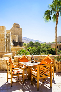 Table and chairs on terrace of Movenpick Dead Sea Spa and Resort with village in background, Madaba Governorate, Jordan