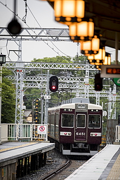 Train departing from railroad station illuminated by glowing lanterns, Arashiyama, Kyoto, Japan