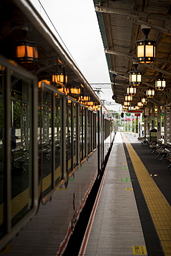 Train waiting at railroad station illuminated by glowing lanterns, Arashiyama, Kyoto, Japan