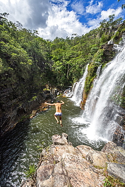 View of adventurous man cliff jumping from waterfall in cerrado, Chapada dos Veadeiros, Goias, Brazil