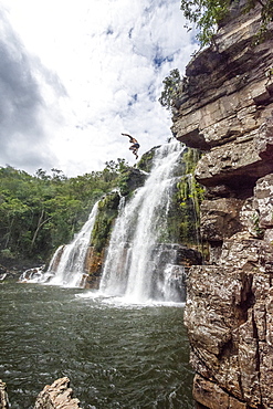 View of adventurous man cliff jumping from waterfall in cerrado, Chapada dos Veadeiros, Goias, Brazil