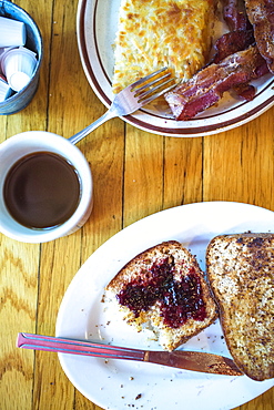 View from above of breakfast on table with toast, hash browns, bacon and coffee