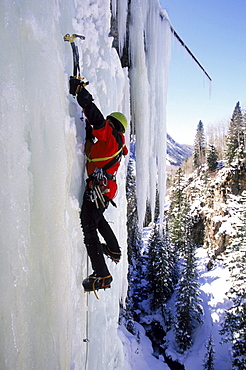 Man gripping icy cliff with axe.