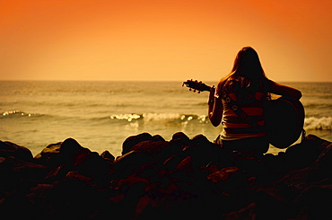 Woman Playing The Guitar And Looking Out To Sea