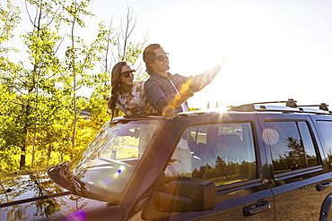 Young couple taking selfies with a cell phone in their vehicle; Edmonton, Alberta, Canada