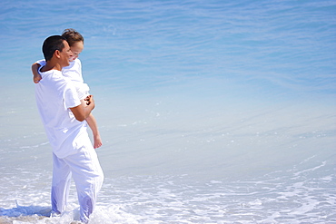 A Father Holds His Child While Standing In The Ocean