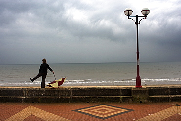 Man With Umbrella Standing By Boardwalk, Yorkshire, England