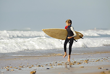 A Boy Running With A Surfboard Down The Beach, Tarifa, Cadiz, Andalusia, Spain