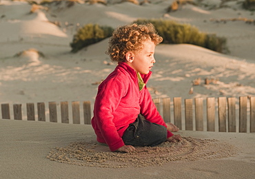 A Young Boy Playing On A Sand Dune, Tarifa, Cadiz, Andalusia, Spain