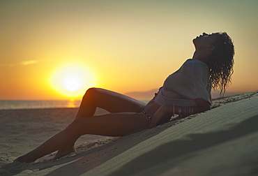 A Woman Wearing A Bathing Suit Lies On The Sand On Los Lances Beach At Sunset, Tarifa, Cadiz, Andalusia, Spain