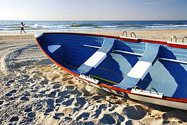 Woman Walking On Beach And Small Boat, New Jersy, Usa.