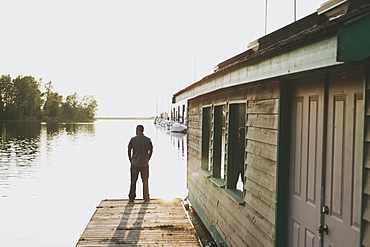 A man standing on the edge of a dock looking out over the ocean, White rock british columbia canada