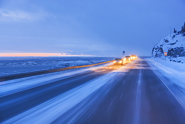 Traffic driving on the seward highway during a snowstorm at twilight in winter, beluga point, Anchorage, alaska, united states of america