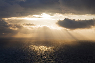 Sunlight streaming through the dark clouds and reflecting on the ocean, County clare, ireland