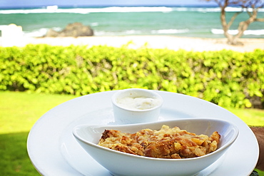 A food item served in a white serving dish with a view of the beach and ocean, Hawaii united states of america