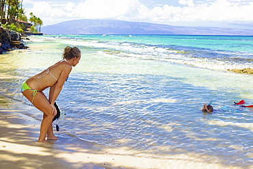 A mother watches her son snorkelling in the shallow water at the beach, Hawaii united states of america