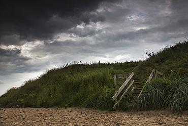 Wooden steps leading to the beach under dark storm clouds, Druridge bay northumberland england