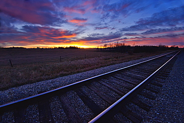 Train tracks and a dramatic colourful sky at sunset, Millet alberta canada