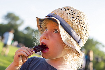 Young Boy Eats A Melting Grape Popsicle In The Sun At The Park, Toronto, Ontario, Canada