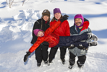 A Young Girl With Three Adults Playing In The Snow, Talkeetna, Alaska, United States Of America