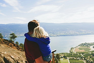 A Father Holds His Young Daughter As They Look Out Over Lake Okanagan, Peachland, British Columbia, Canada