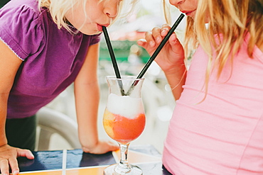 Two Young Girls Share A Drink With Straws, Peachland, British Columbia, Canada