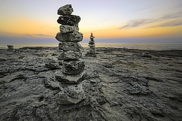 Rock Sculptures Dot The Shoreline As The Sun Dips Below The Horizon In Cave Point, Sturgeon Bay, Wisconsin, United States Of America