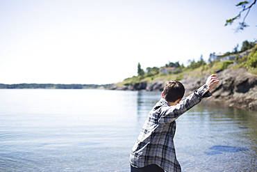 A Boy Throws Rocks Into The Water, Victoria, British Columbia, Canada