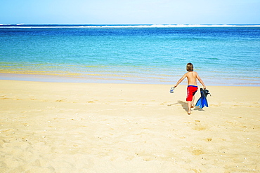 A Boy Running Out To The Ocean Across The Beach With Snorkelling Gear, Kauai, Hawaii, United States Of America