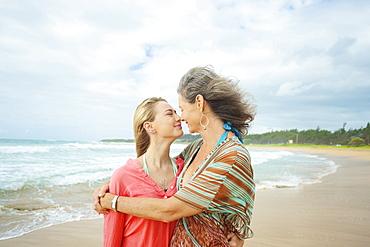 A Mother And Daughter Together On The Beach At The Water's Edge, Kauai, Hawaii, United States Of America