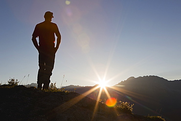 A Man Stands On A Ridge Overlooking The Landscape With Bright Sun Rays, Kananaskis, Alberta, Canada