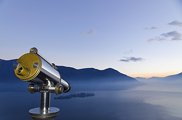 Binoculars With A View Of A Mountainous Landscape And Fog Over Lake Maggiore, Isole Di Brissago, Ticino, Switzerland