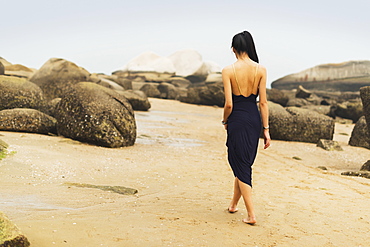 A Model In Formal Dress Walks Barefoot On The Sandy Beach, Xiamen, China