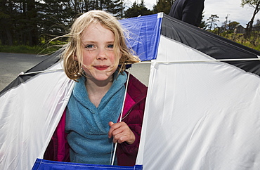 Young Girl Holding A Kite With Her Head Poking Through An Opening In The Kite, Bishops Beach, Katchemak Bay, Homer, Alaska, United States Of America