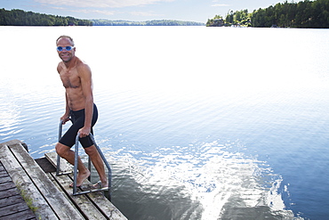 Man Getting Out Of The Water Onto A Dock, Morbylanga, Sweden