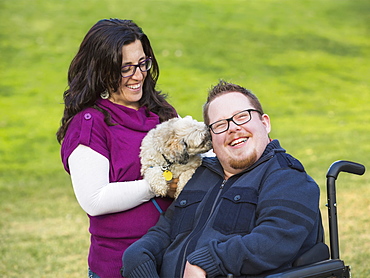 Disabled Husband With His Wife And Their Pet Dog In A Park In Autumn, Edmonton, Alberta, Canada