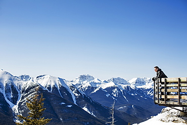 A Man Stands With A View From Sulphur Mountain Of The Canadian Rockies In Winter, Banff, Alberta, Canada