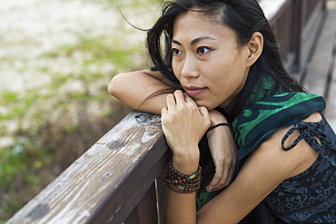 A Young Woman Sits Against A Wooden Railing Looking Out At The Ocean, Jincheng, Kinmen, Taiwan