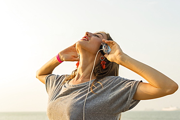 Young Woman Listening To Music With Her Headphones On The Beach, Xiamen, China