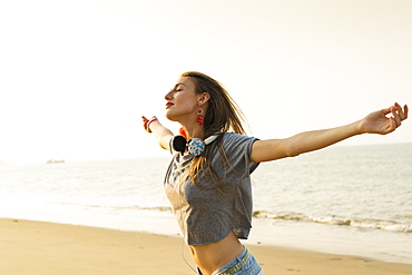 Young Woman Listening To Music With Her Headphones On The Beach, Xiamen, China