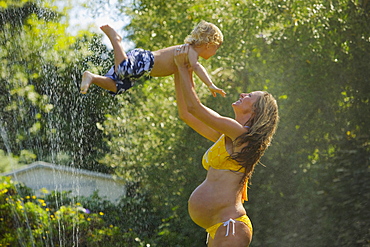 A Pregnant Mother Plays In The Water With Her Young Son, Santa Barbara, California, United States Of America