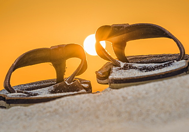 Brown Leather Sandals On The Sand With A Glowing Orange Sky And Sun, Spain