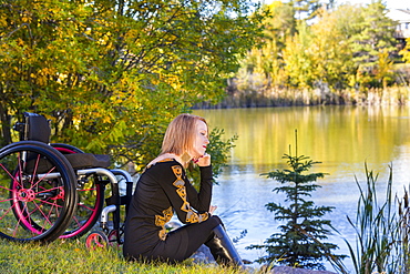 Young Disabled Woman Sitting Beside Her Wheelchair In A City Park In Autumn, Edmonton, Alberta, Canada