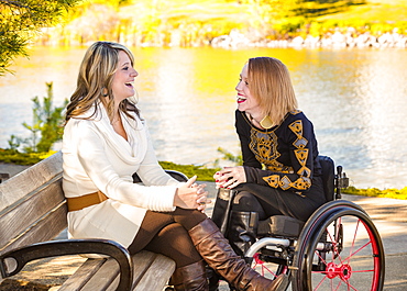 Young Paraplegic Woman And Her Friend Spending Quality Time Together In A City Park In Autumn, Edmonton, Alberta, Canada